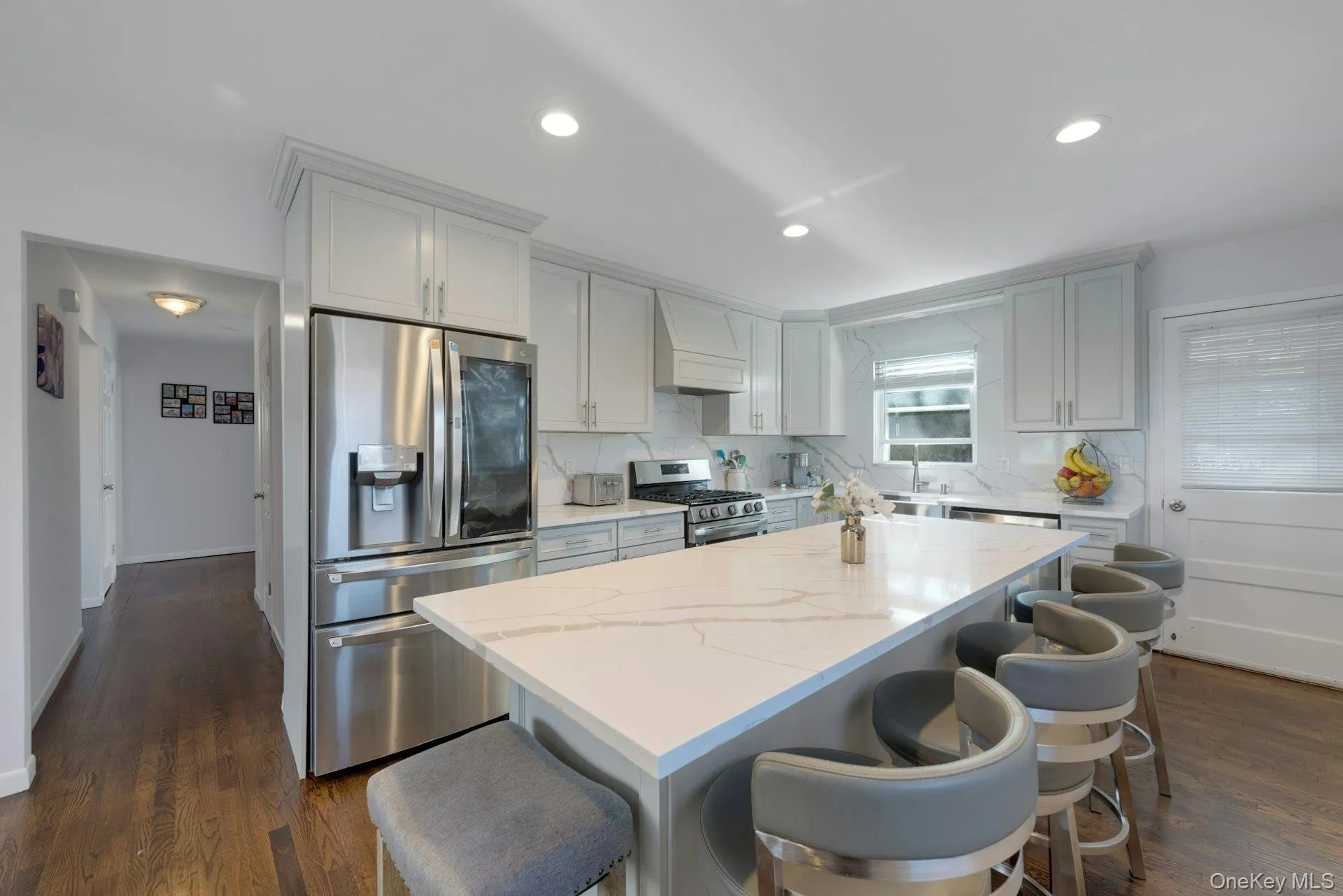 Kitchen with custom range hood, stainless steel appliances, a kitchen island, and dark wood-type flooring Kitchen with custom range hood, stainless steel appliances, a kitchen island, and dark wood-type flooring