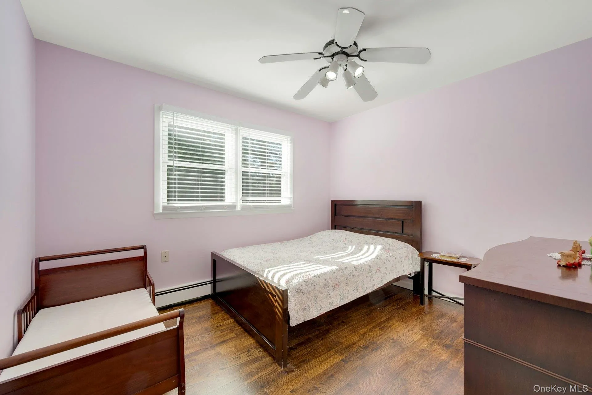 Bedroom featuring a baseboard heating unit, ceiling fan, and dark wood-type flooring Bedroom featuring a baseboard heating unit, ceiling fan, and dark wood-type flooring
