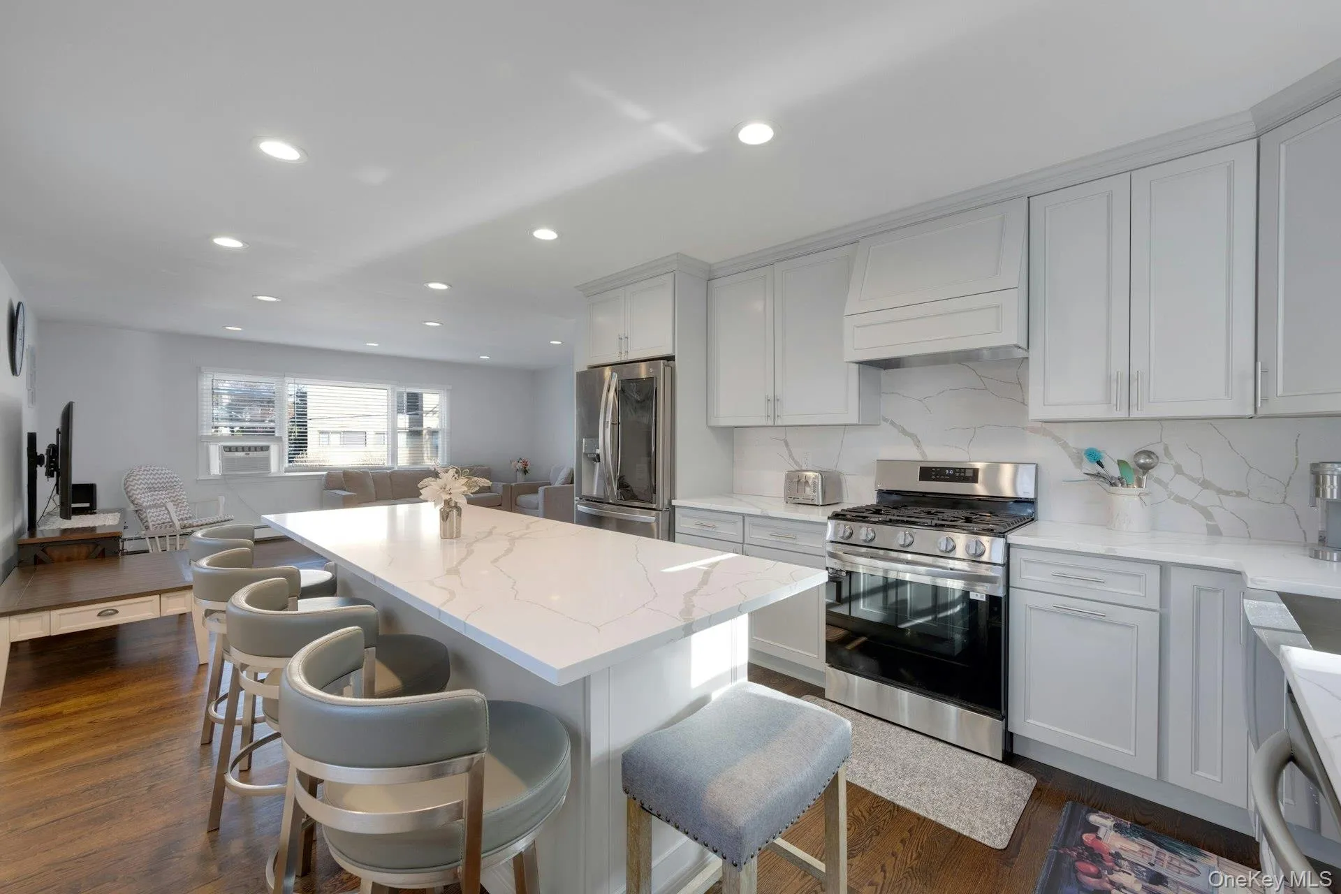Kitchen featuring a center island, light stone countertops, appliances with stainless steel finishes, dark hardwood / wood-style flooring, and a breakfast bar area Kitchen featuring a center island, light stone countertops, appliances with stainless steel finishes, dark hardwood / wood-style flooring, and a breakfast bar area