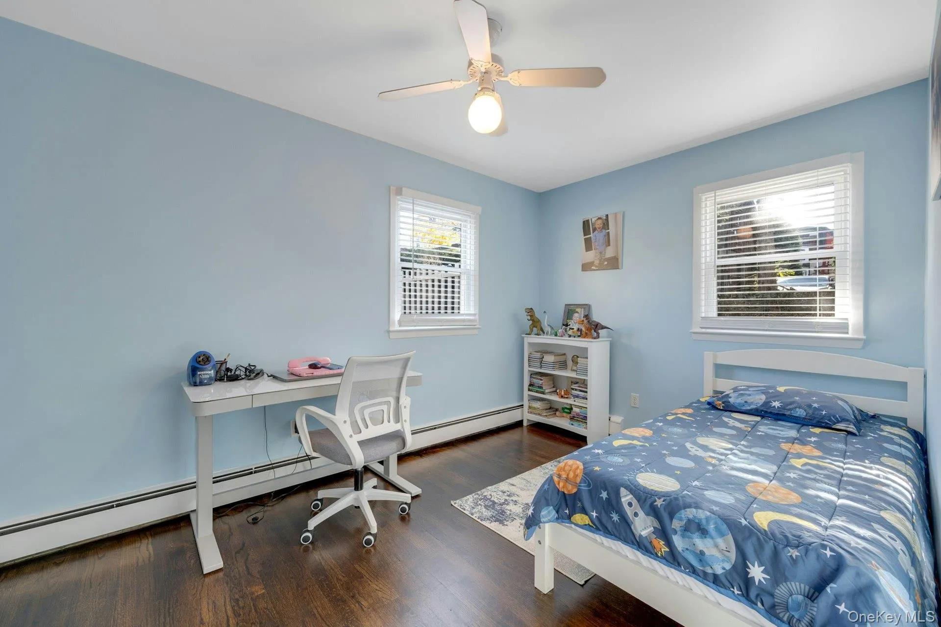 Bedroom featuring ceiling fan, dark wood-type flooring, and a baseboard heating unit Bedroom featuring ceiling fan, dark wood-type flooring, and a baseboard heating unit