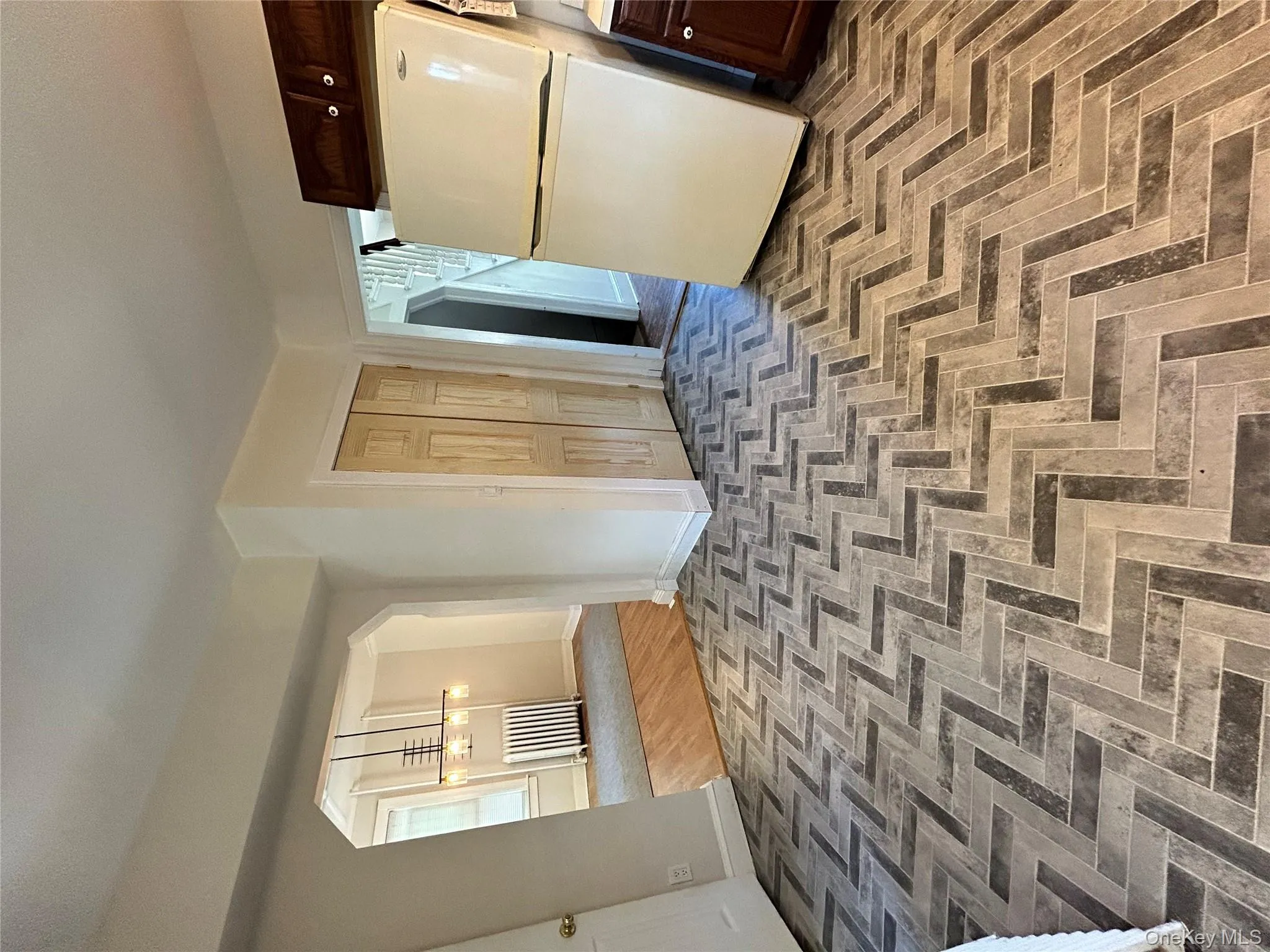 Kitchen featuring arched walkways, baseboards, dark brown cabinetry, and fridge Kitchen featuring arched walkways, baseboards, dark brown cabinetry, and fridge
