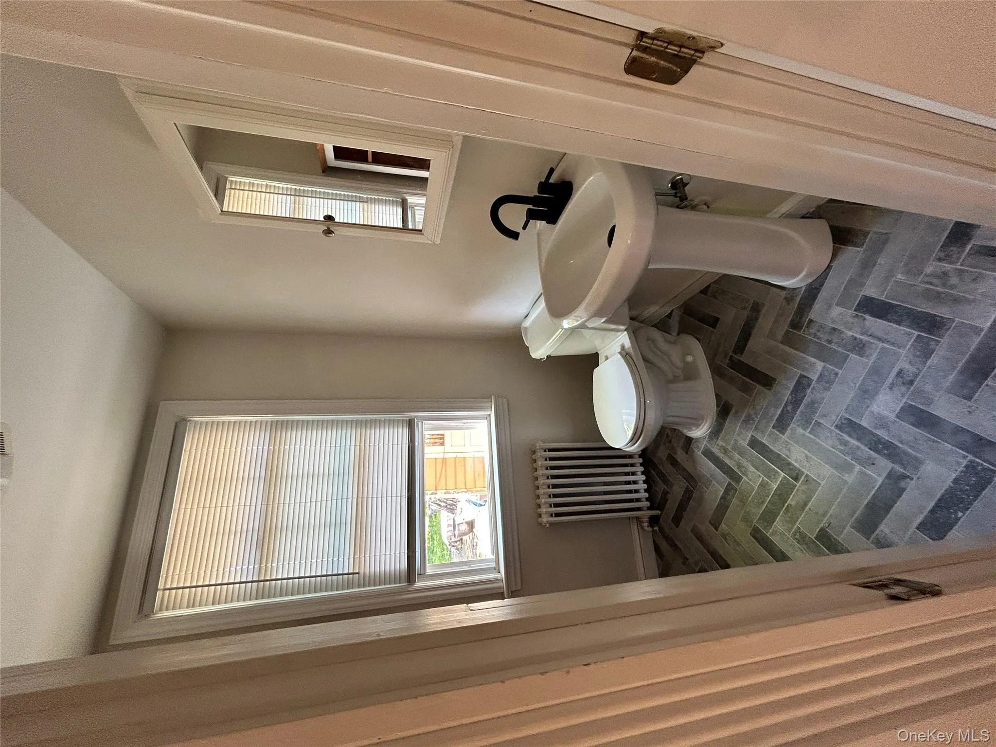 Half bath with baseboards, radiator, brick floor, and toilet Half bath with baseboards, radiator, brick floor, and toilet