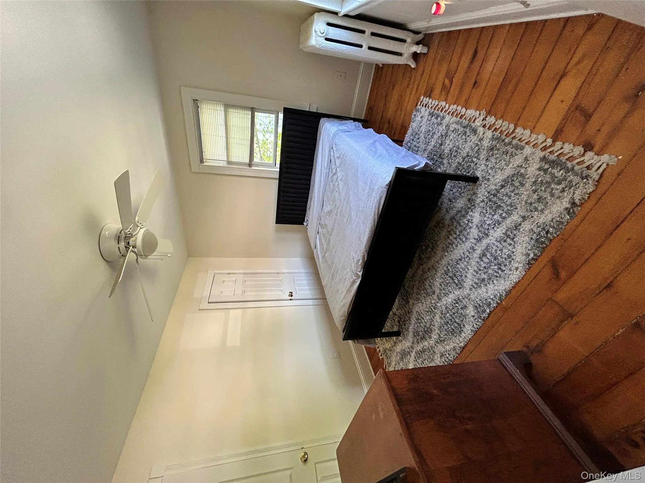 Bedroom with baseboards, ceiling fan, wood finished floors, and radiator Bedroom with baseboards, ceiling fan, wood finished floors, and radiator