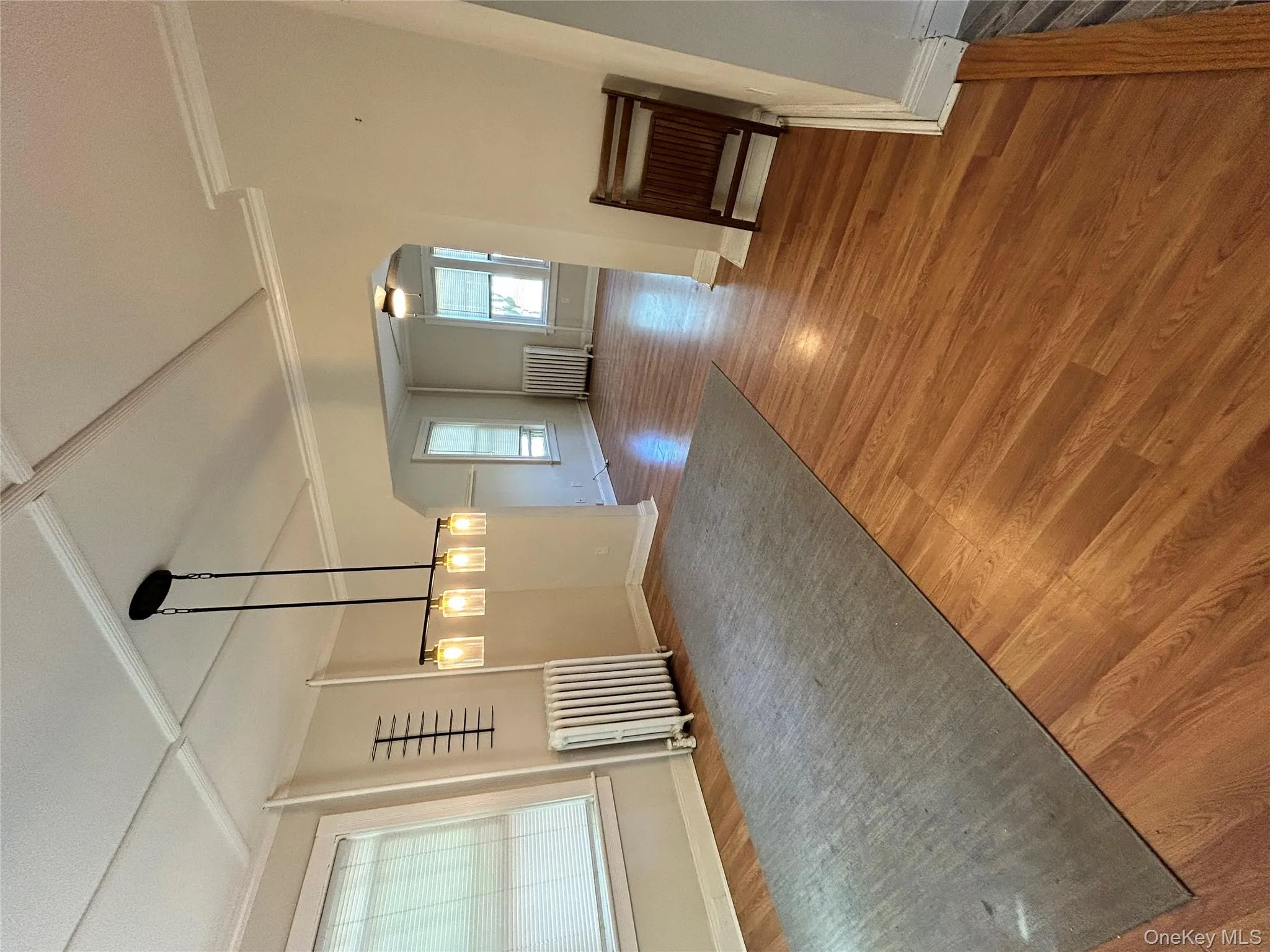 Unfurnished dining area featuring baseboards, ceiling fan, radiator heating unit, and wood finished floors Unfurnished dining area featuring baseboards, ceiling fan, radiator heating unit, and wood finished floors