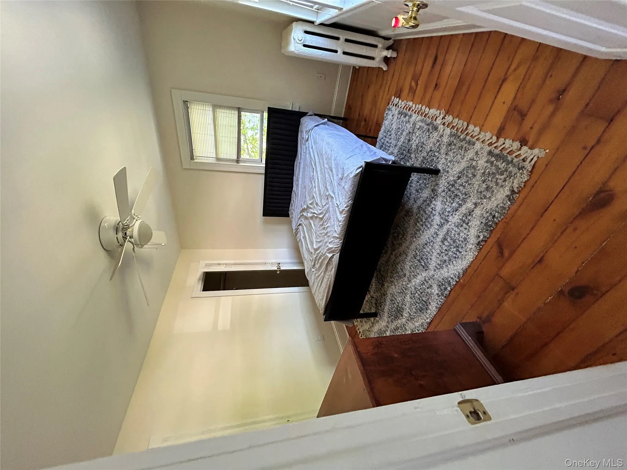 Bedroom with radiator, ceiling fan, baseboards, and wood finished floors Bedroom with radiator, ceiling fan, baseboards, and wood finished floors