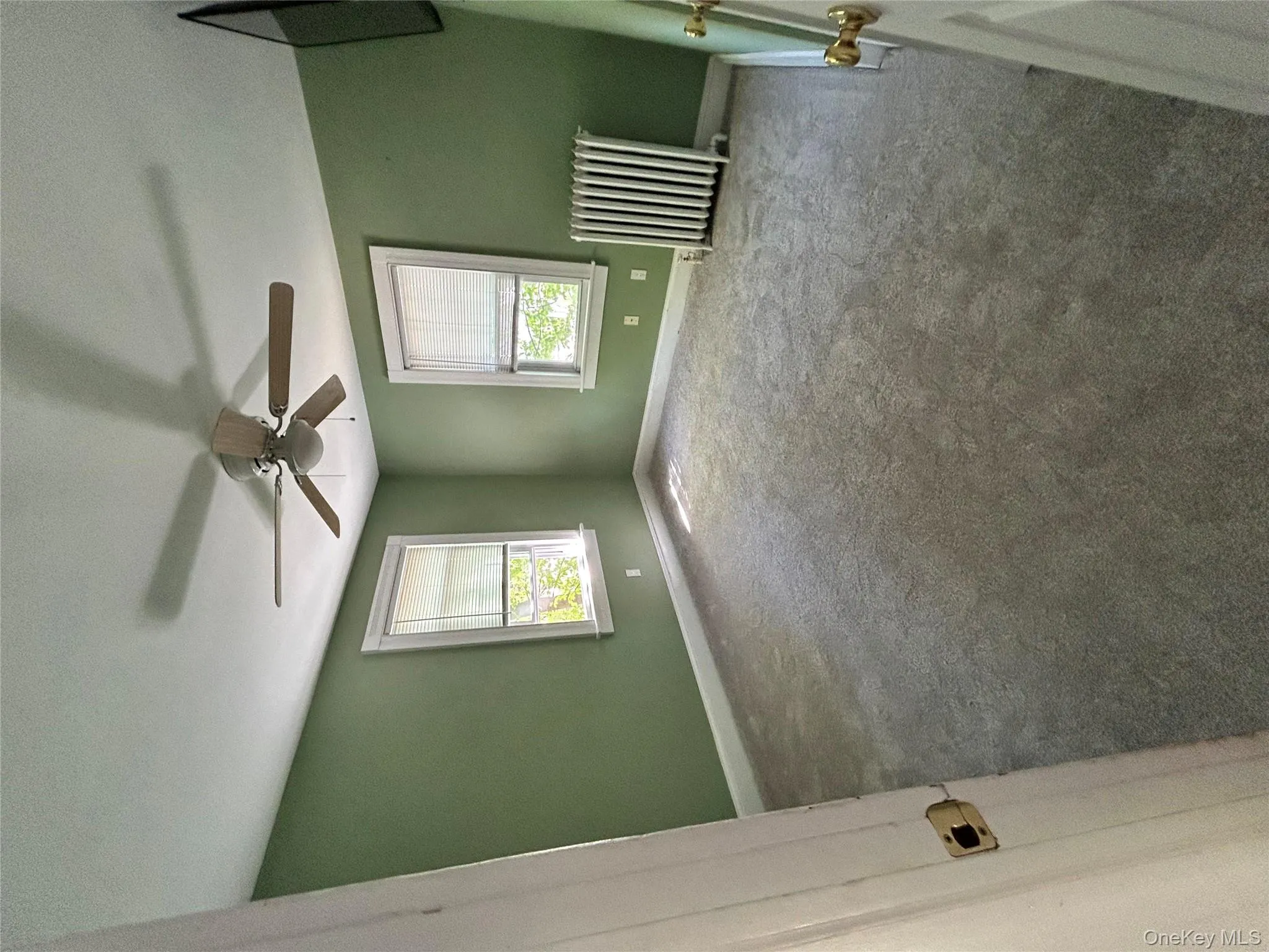 Unfurnished room featuring carpet flooring, a ceiling fan, baseboards, and radiator heating unit Unfurnished room featuring carpet flooring, a ceiling fan, baseboards, and radiator heating unit