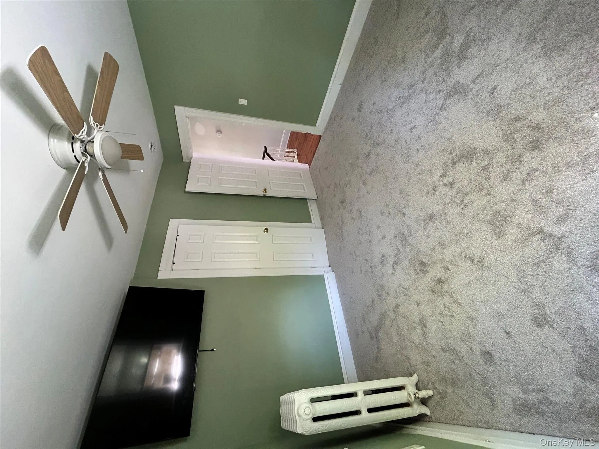 Unfurnished bedroom featuring radiator heating unit, carpet floors, baseboards, and a ceiling fan Unfurnished bedroom featuring radiator heating unit, carpet floors, baseboards, and a ceiling fan