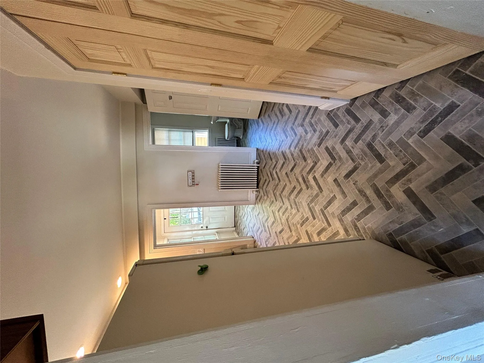 Hall with plenty of natural light, brick floor, and radiator heating unit Hall with plenty of natural light, brick floor, and radiator heating unit