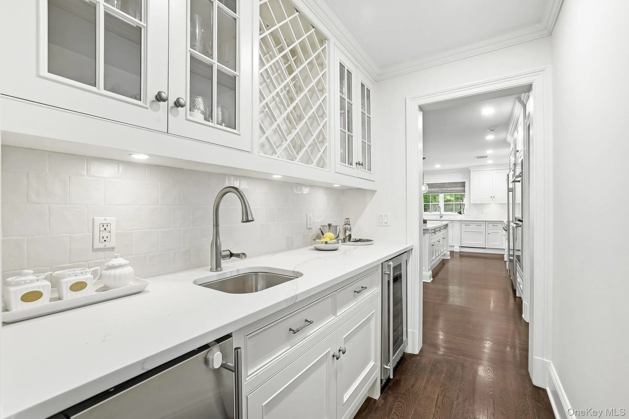 Chic butler’s pantry with glass cabinetry, wine refrigerator, sink and ice maker. Chic butler’s pantry with glass cabinetry, wine refrigerator, sink and ice maker.