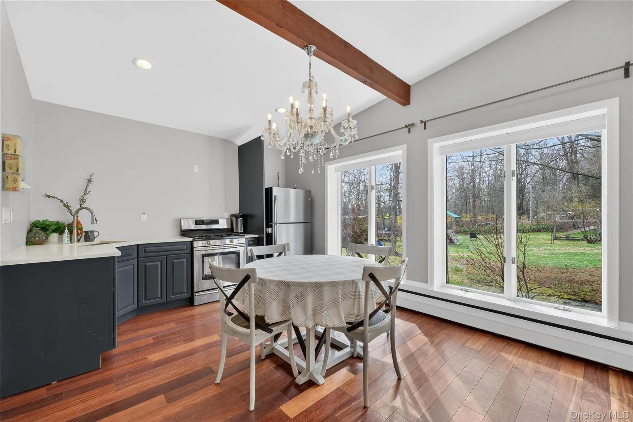 Dining area featuring vaulted ceiling with beams, a chandelier, dark wood-style flooring, and a baseboard radiator Dining area featuring vaulted ceiling with beams, a chandelier, dark wood-style flooring, and a baseboard radiator