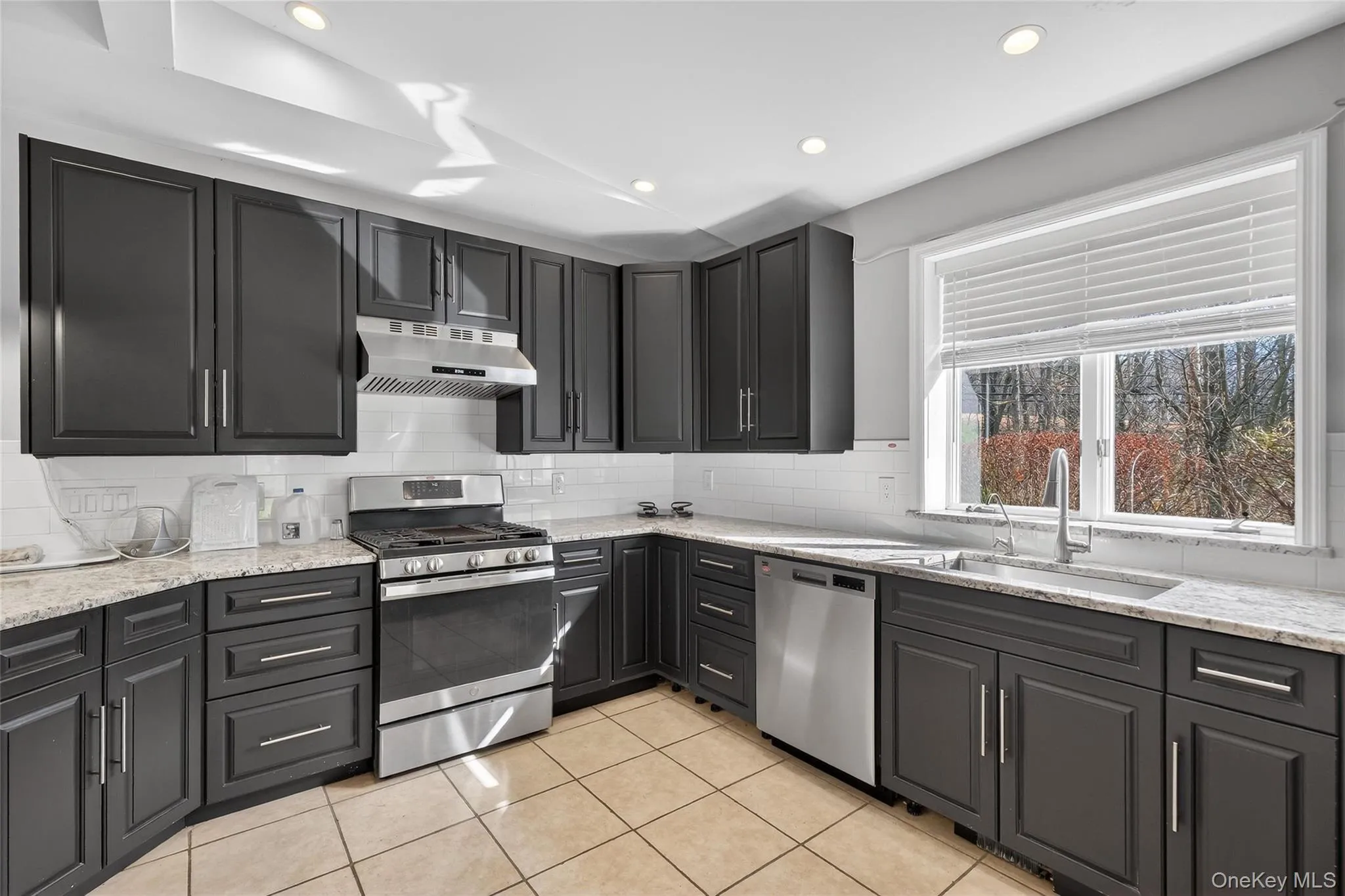 Kitchen with stainless steel appliances, light stone counters, recessed lighting, light tile patterned floors, and backsplash Kitchen with stainless steel appliances, light stone counters, recessed lighting, light tile patterned floors, and backsplash