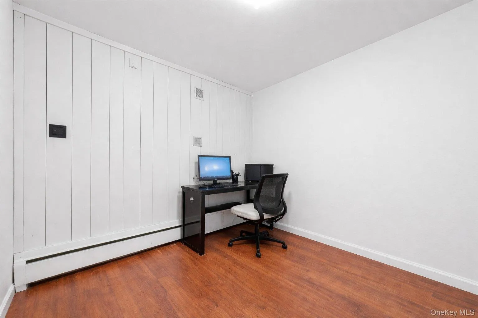 Home office with light wood-type flooring and a baseboard radiator Home office with light wood-type flooring and a baseboard radiator