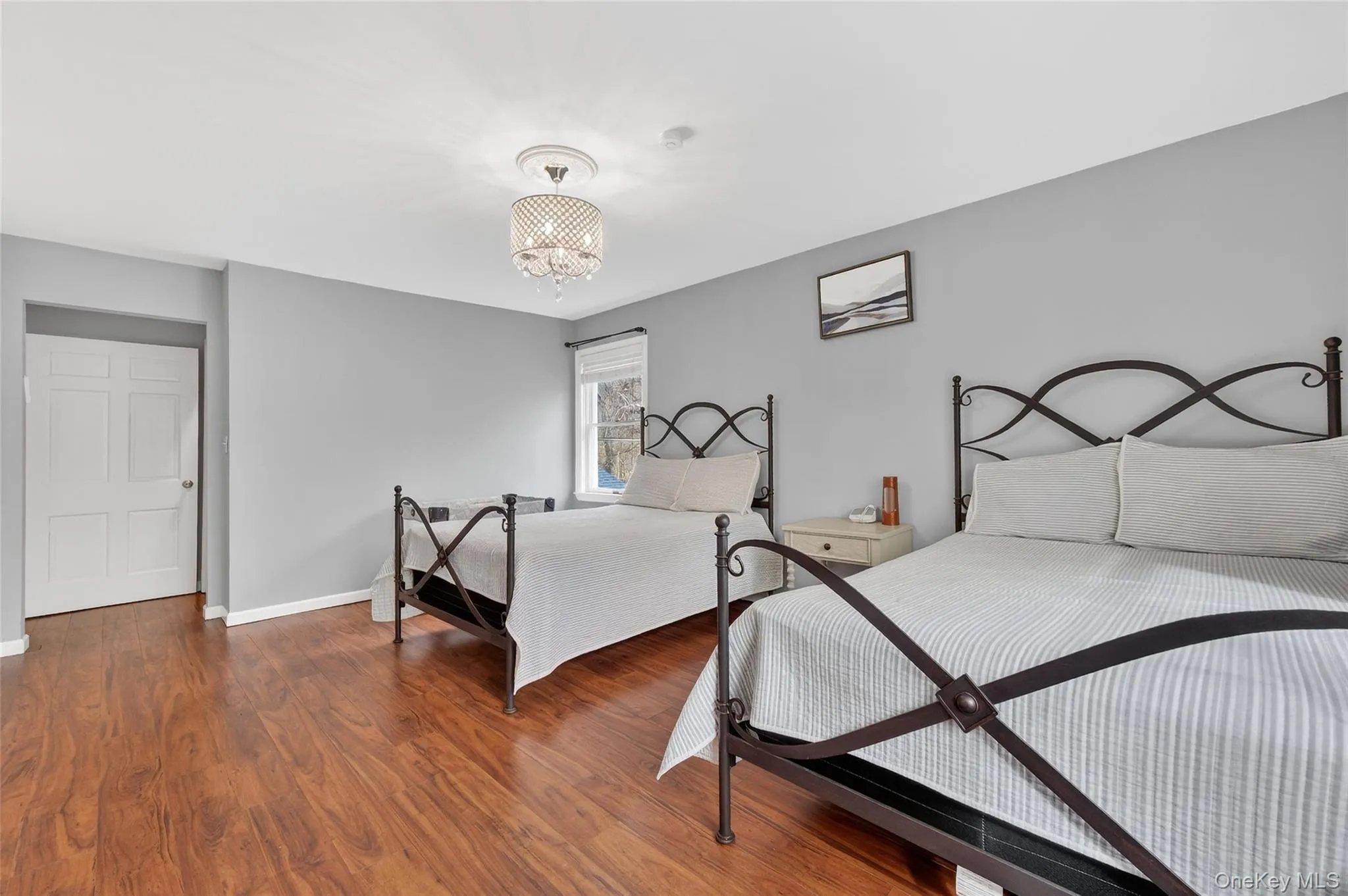 Bedroom featuring wood finished floors and a chandelier Bedroom featuring wood finished floors and a chandelier