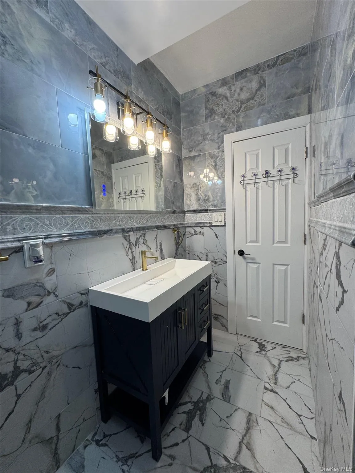 Bathroom with tile walls, vanity, and light marble finish flooring Bathroom with tile walls, vanity, and light marble finish flooring