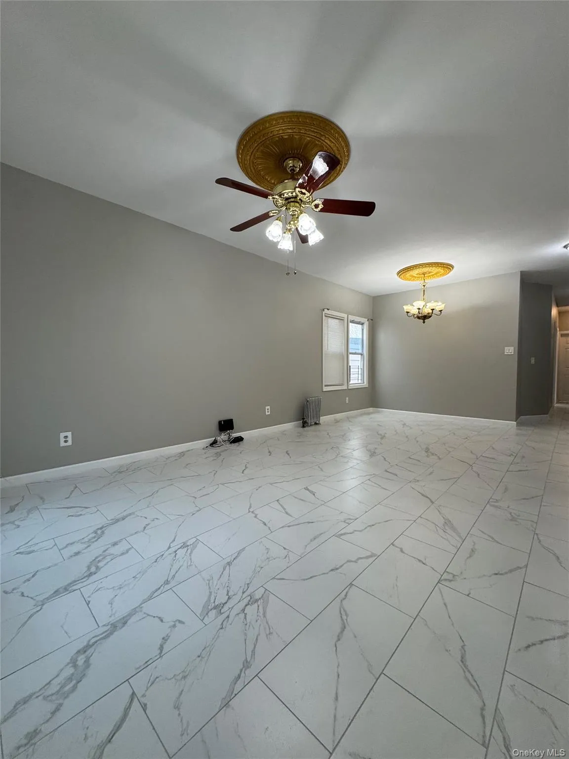 Empty room with light marble finish floors, ceiling fan, and a chandelier Empty room with light marble finish floors, ceiling fan, and a chandelier