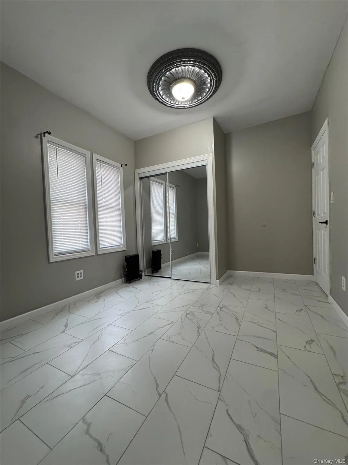 Unfurnished bedroom featuring light marble finish flooring and a closet Unfurnished bedroom featuring light marble finish flooring and a closet