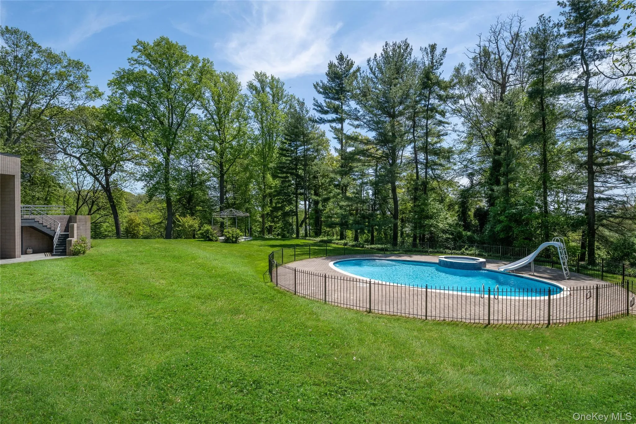 View of pool featuring a water slide, stairway, an in-ground hot tub, and a gazebo View of pool featuring a water slide, stairway, an in-ground hot tub, and a gazebo
