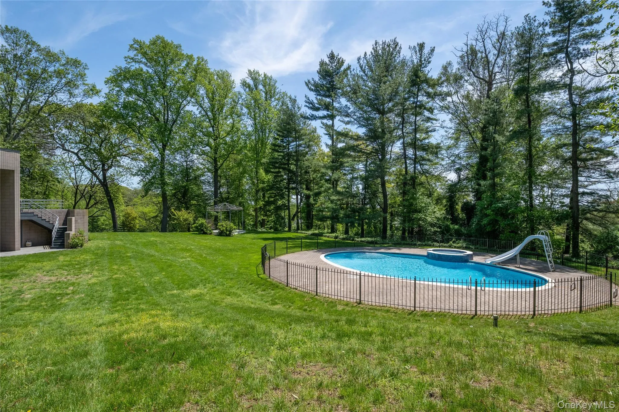 View of swimming pool with a water slide, stairs, and an in-ground hot tub View of swimming pool with a water slide, stairs, and an in-ground hot tub