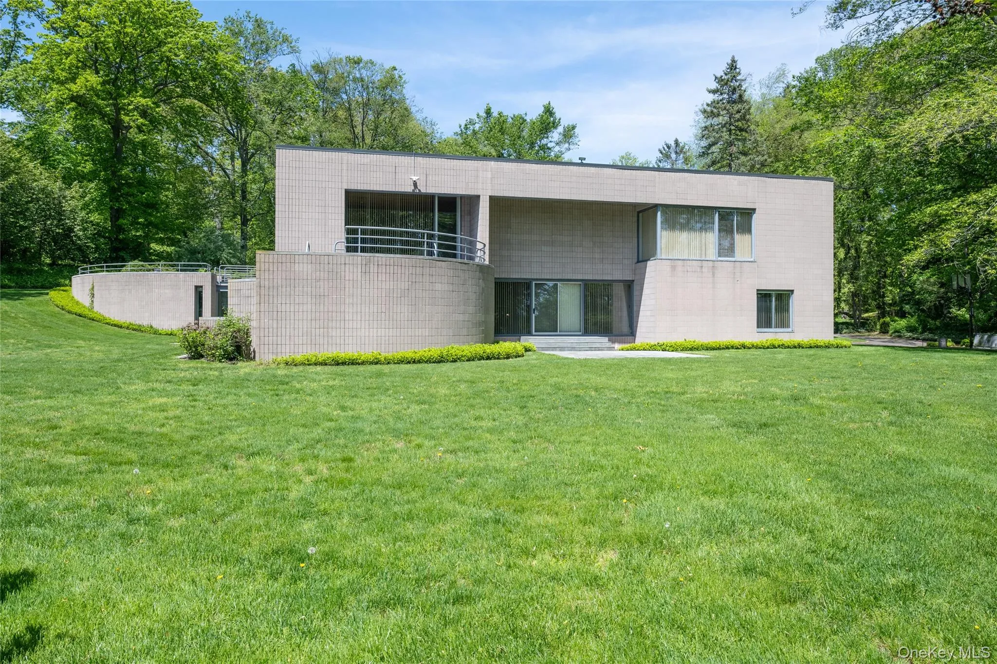 View of front of home featuring a front lawn, concrete block siding, and a balcony View of front of home featuring a front lawn, concrete block siding, and a balcony