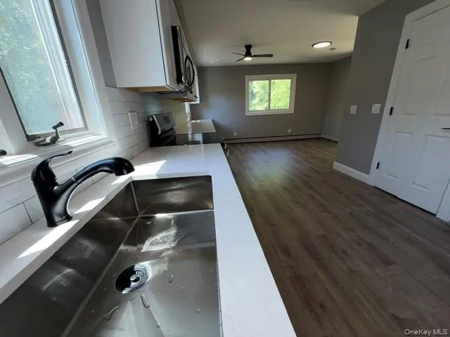 Modern kitchen sink with a matte black pull-down faucet, white countertop, and subway tile backsplash Modern kitchen sink with a matte black pull-down faucet, white countertop, and subway tile backsplash