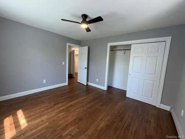 Room featuring rich wood-finish flooring, neutral gray walls, and white trim Room featuring rich wood-finish flooring, neutral gray walls, and white trim