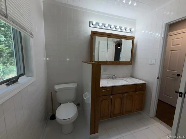Compact bathroom featuring white tile walls and flooring Compact bathroom featuring white tile walls and flooring