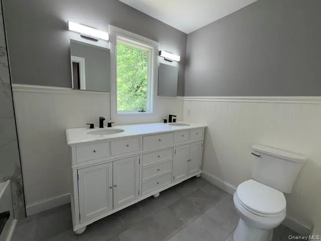 Dual vanity with white cabinetry, integrated sinks, and matte black fixtures Dual vanity with white cabinetry, integrated sinks, and matte black fixtures
