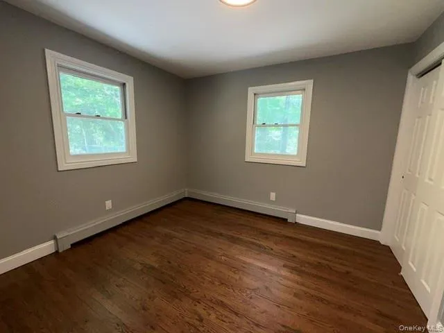 Interior space featuring wood-finish flooring, two white-framed windows, and a flush-mount ceiling light Interior space featuring wood-finish flooring, two white-framed windows, and a flush-mount ceiling light