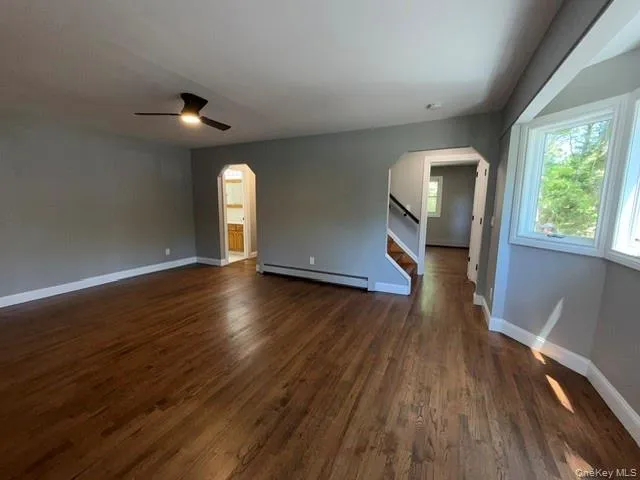 Spacious interior featuring wood-finish flooring, light gray walls, and white trim Spacious interior featuring wood-finish flooring, light gray walls, and white trim