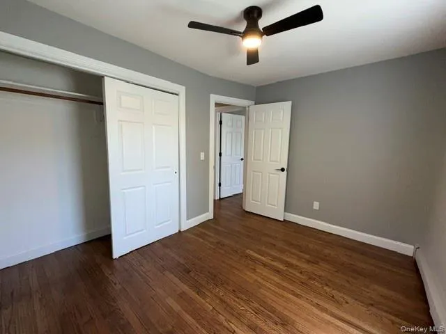 Bedroom featuring wood-finish flooring, neutral gray walls, a ceiling fan with integrated lighting, and white bi-fold closet doors Bedroom featuring wood-finish flooring, neutral gray walls, a ceiling fan with integrated lighting, and white bi-fold closet doors