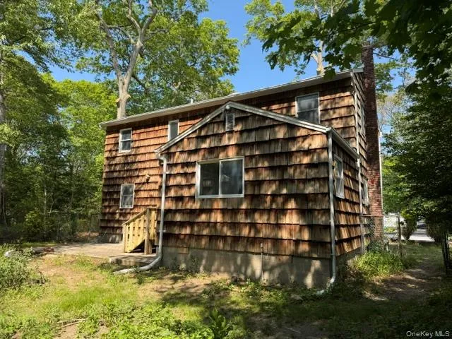 Wood shingle siding exterior featuring multiple windows and a brick chimney Wood shingle siding exterior featuring multiple windows and a brick chimney
