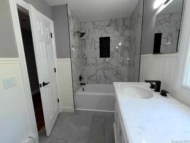 Bathroom featuring a tub/shower combination with white marble-look tile surround and black recessed niche Bathroom featuring a tub/shower combination with white marble-look tile surround and black recessed niche
