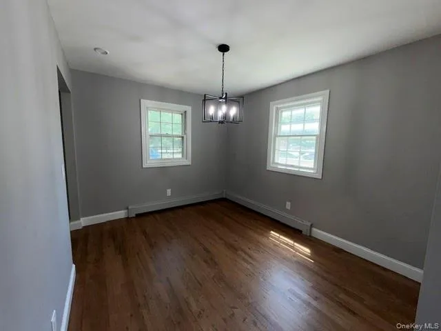 Room featuring wood-finish flooring and a contemporary black chandelier Room featuring wood-finish flooring and a contemporary black chandelier