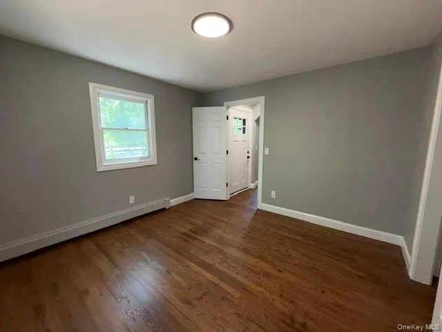 Room featuring wood flooring, neutral wall paint, and white trim Room featuring wood flooring, neutral wall paint, and white trim