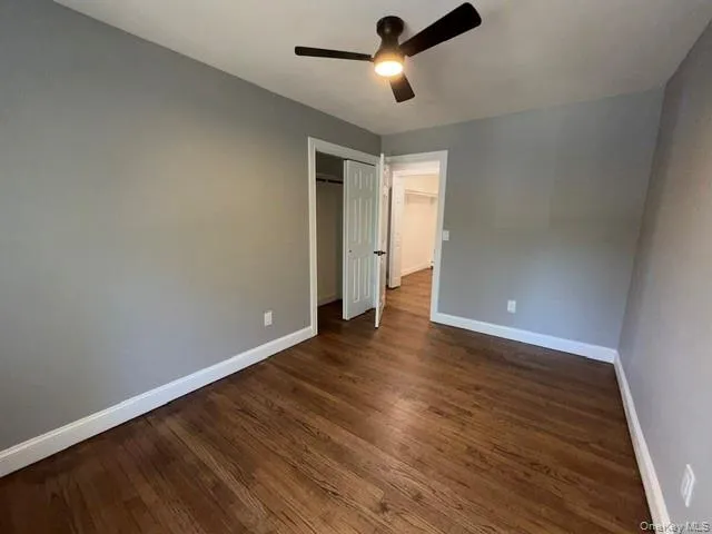 Room featuring wood-finish flooring, light grey painted walls, white baseboards, and a ceiling fan with integrated lighting Room featuring wood-finish flooring, light grey painted walls, white baseboards, and a ceiling fan with integrated lighting