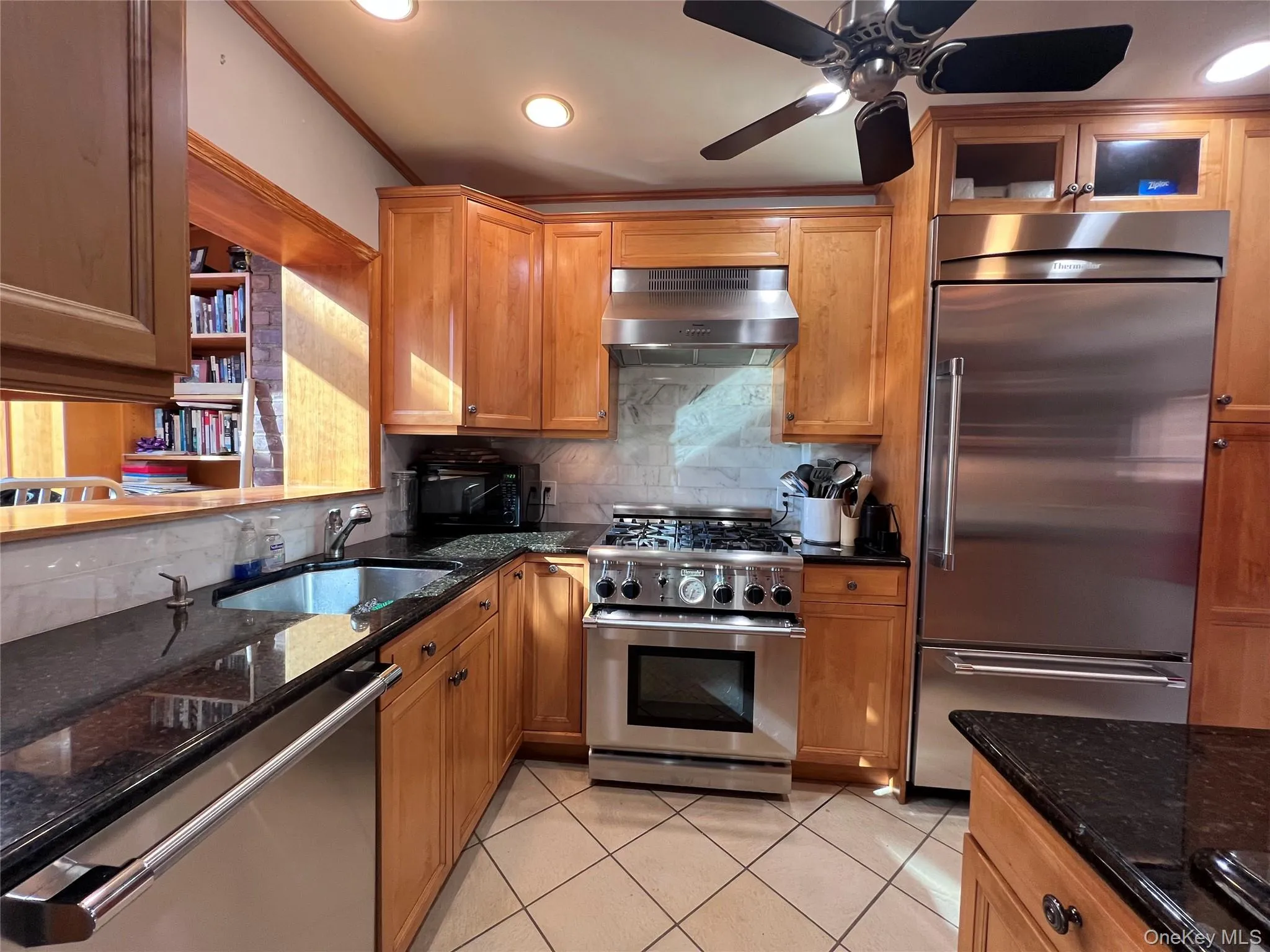 Kitchen with stainless steel thermadoor appliances, granite counters and marble tile backsplash. Ceiling fan and window to solarium, library/ office room. Kitchen with stainless steel thermadoor appliances, granite counters and marble tile backsplash. Ceiling fan and window to solarium, library/ office room.