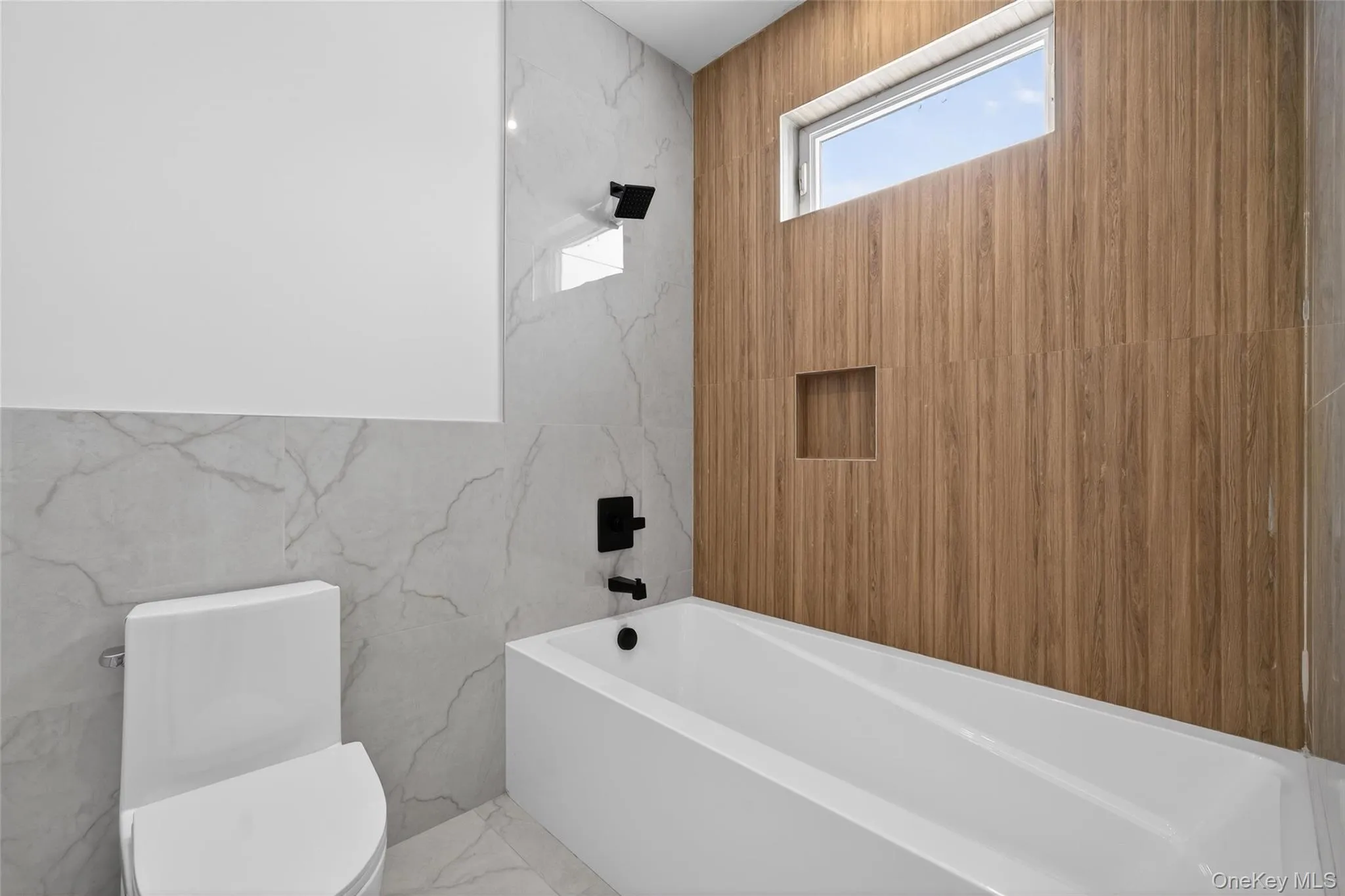 Bathroom with marble tiled floors, stone wall, tub / shower combination, and tile walls Bathroom with marble tiled floors, stone wall, tub / shower combination, and tile walls