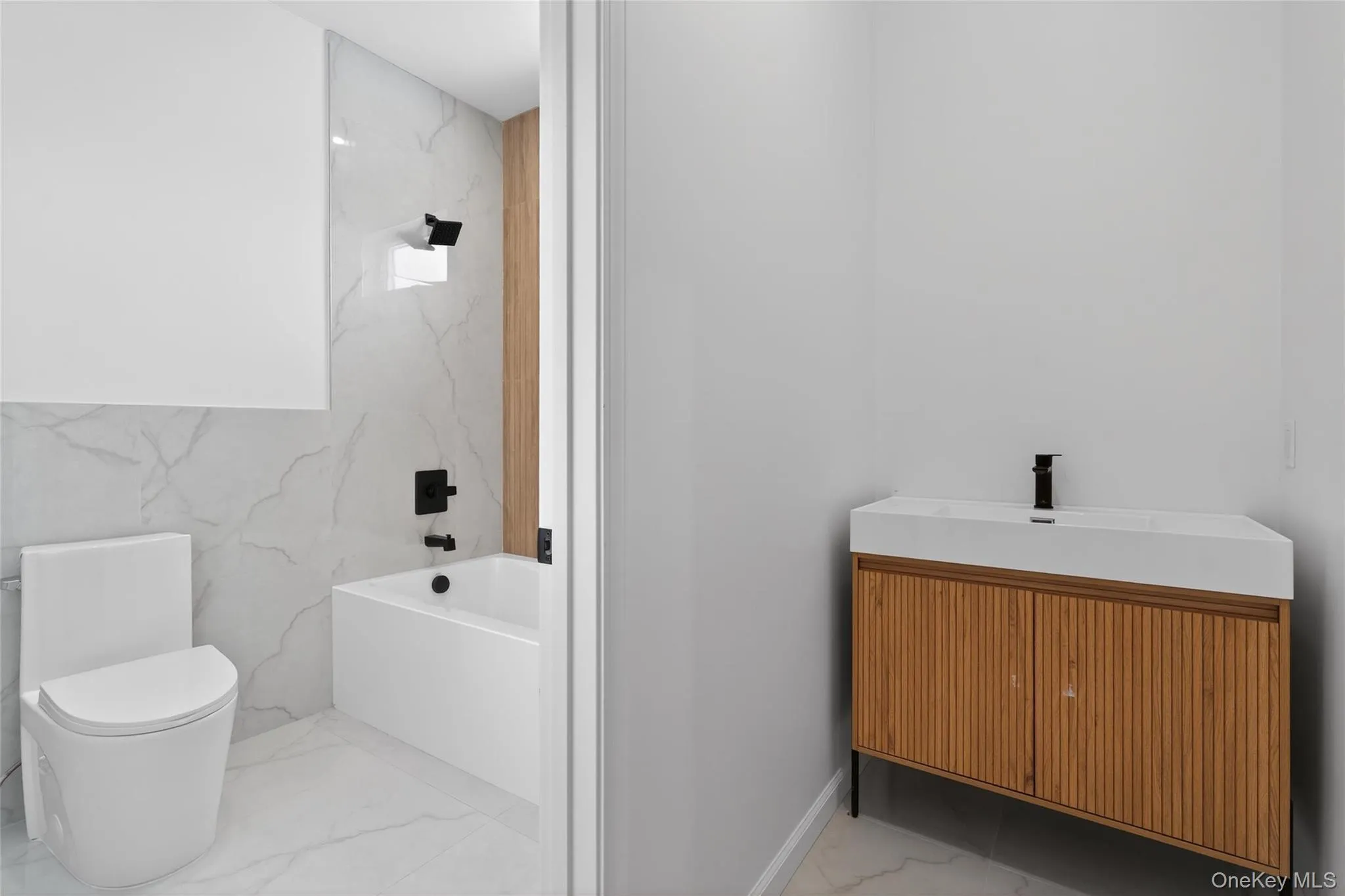 Bathroom with light marble finish flooring, vanity, a bath, and stone wall Bathroom with light marble finish flooring, vanity, a bath, and stone wall