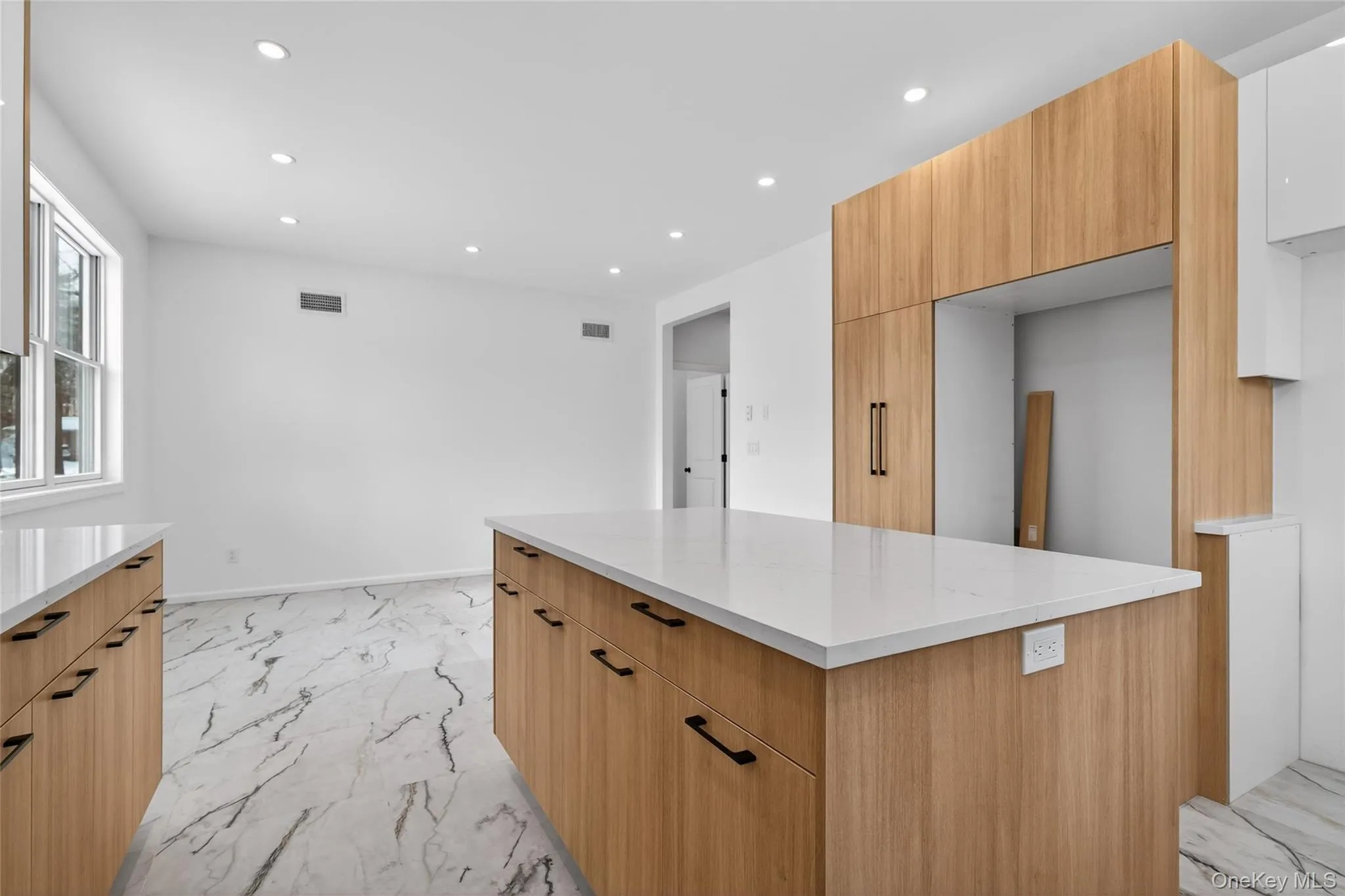 Kitchen featuring recessed lighting, light marble finish flooring, modern cabinets, a kitchen island, and light stone countertops Kitchen featuring recessed lighting, light marble finish flooring, modern cabinets, a kitchen island, and light stone countertops