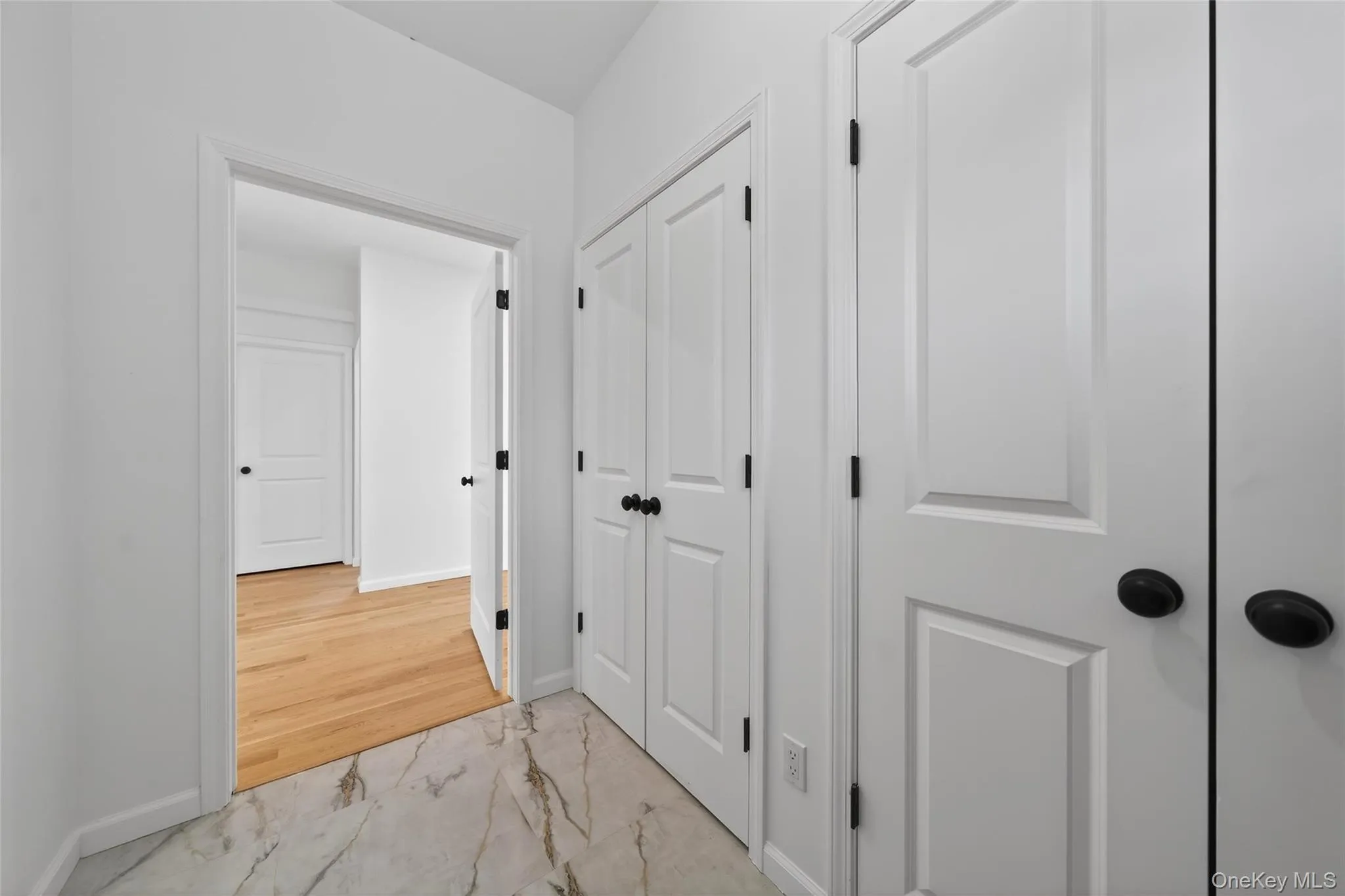 Hallway featuring light marble finish flooring and baseboards Hallway featuring light marble finish flooring and baseboards