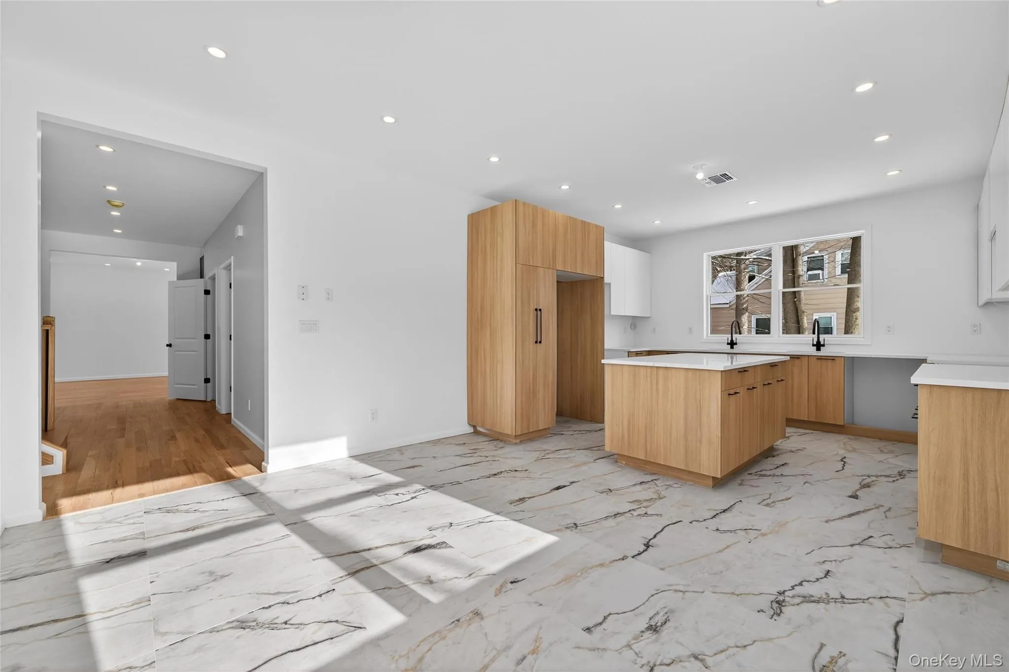 Kitchen featuring recessed lighting, light brown cabinetry, a kitchen island, light marble finish flooring, and modern cabinets Kitchen featuring recessed lighting, light brown cabinetry, a kitchen island, light marble finish flooring, and modern cabinets