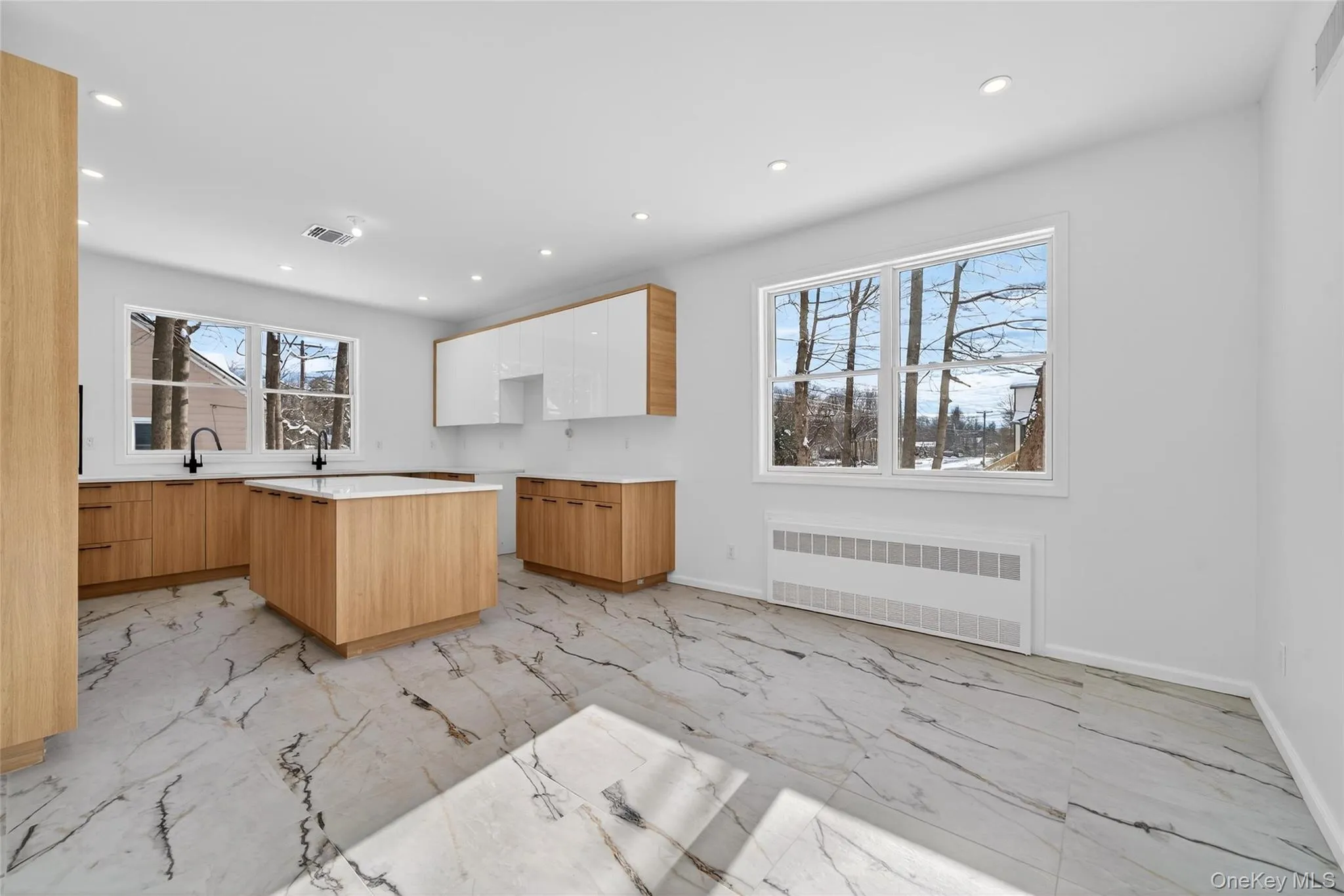 Kitchen featuring modern cabinets, radiator, light marble finish flooring, a kitchen island, and recessed lighting Kitchen featuring modern cabinets, radiator, light marble finish flooring, a kitchen island, and recessed lighting