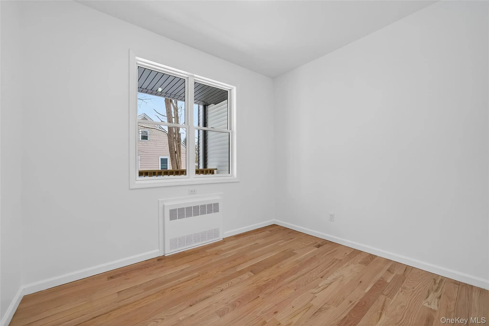 Unfurnished room with radiator heating unit and light wood-style floors Unfurnished room with radiator heating unit and light wood-style floors