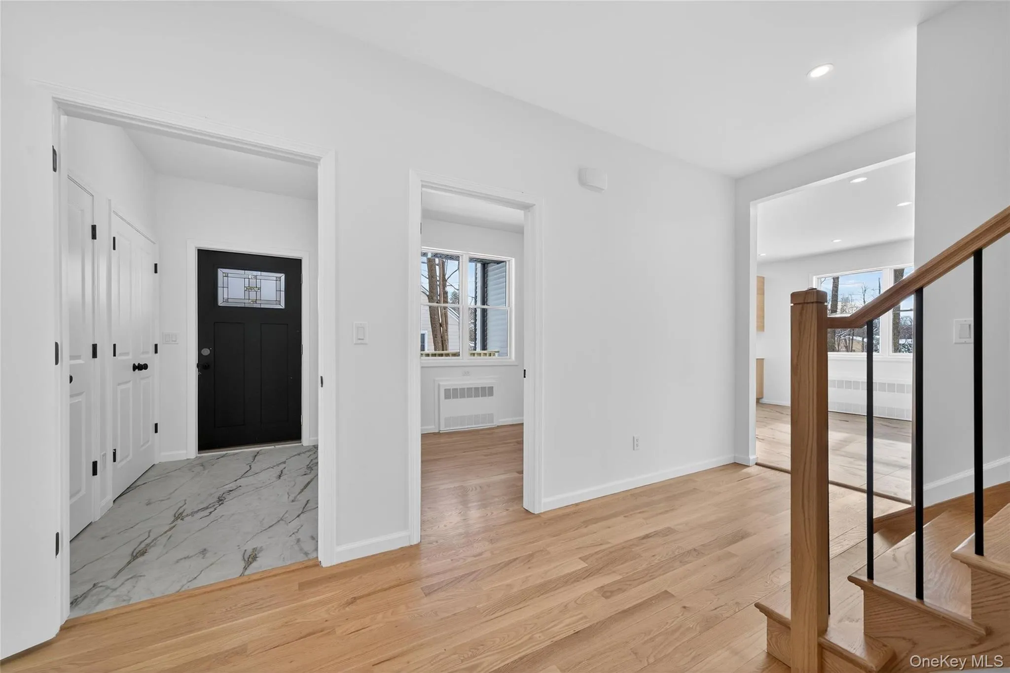 Foyer featuring stairs, light wood-style floors, recessed lighting, and radiator Foyer featuring stairs, light wood-style floors, recessed lighting, and radiator