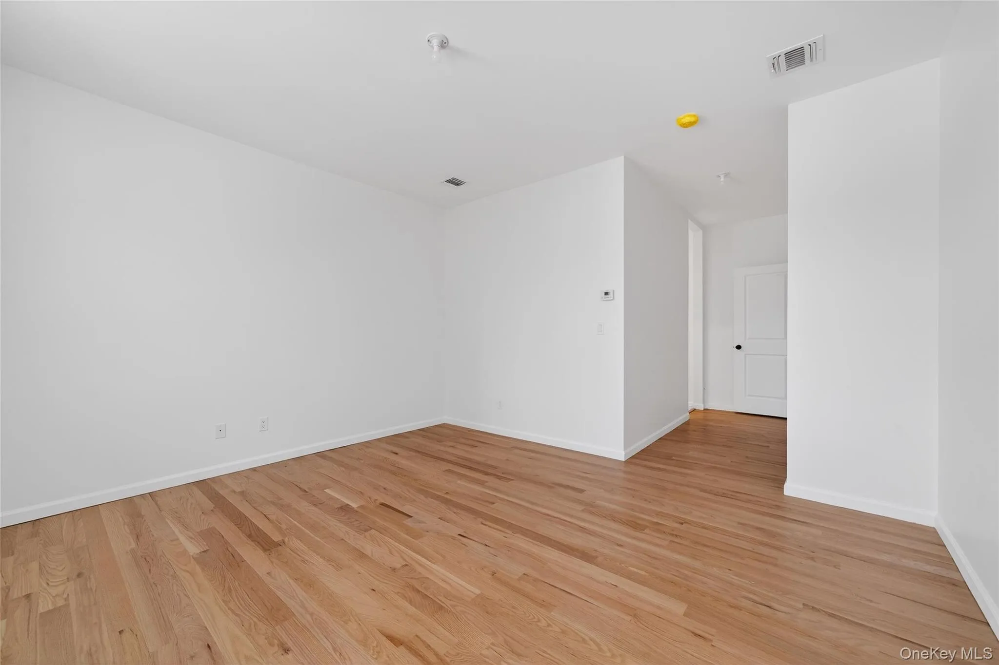 Spare room featuring light wood-style floors and baseboards Spare room featuring light wood-style floors and baseboards