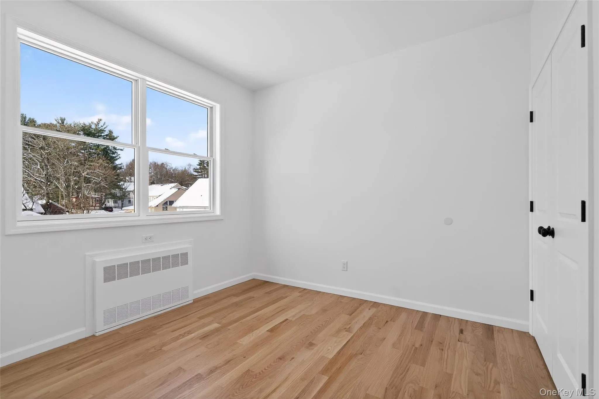 Empty room featuring radiator heating unit and light wood-style floors Empty room featuring radiator heating unit and light wood-style floors