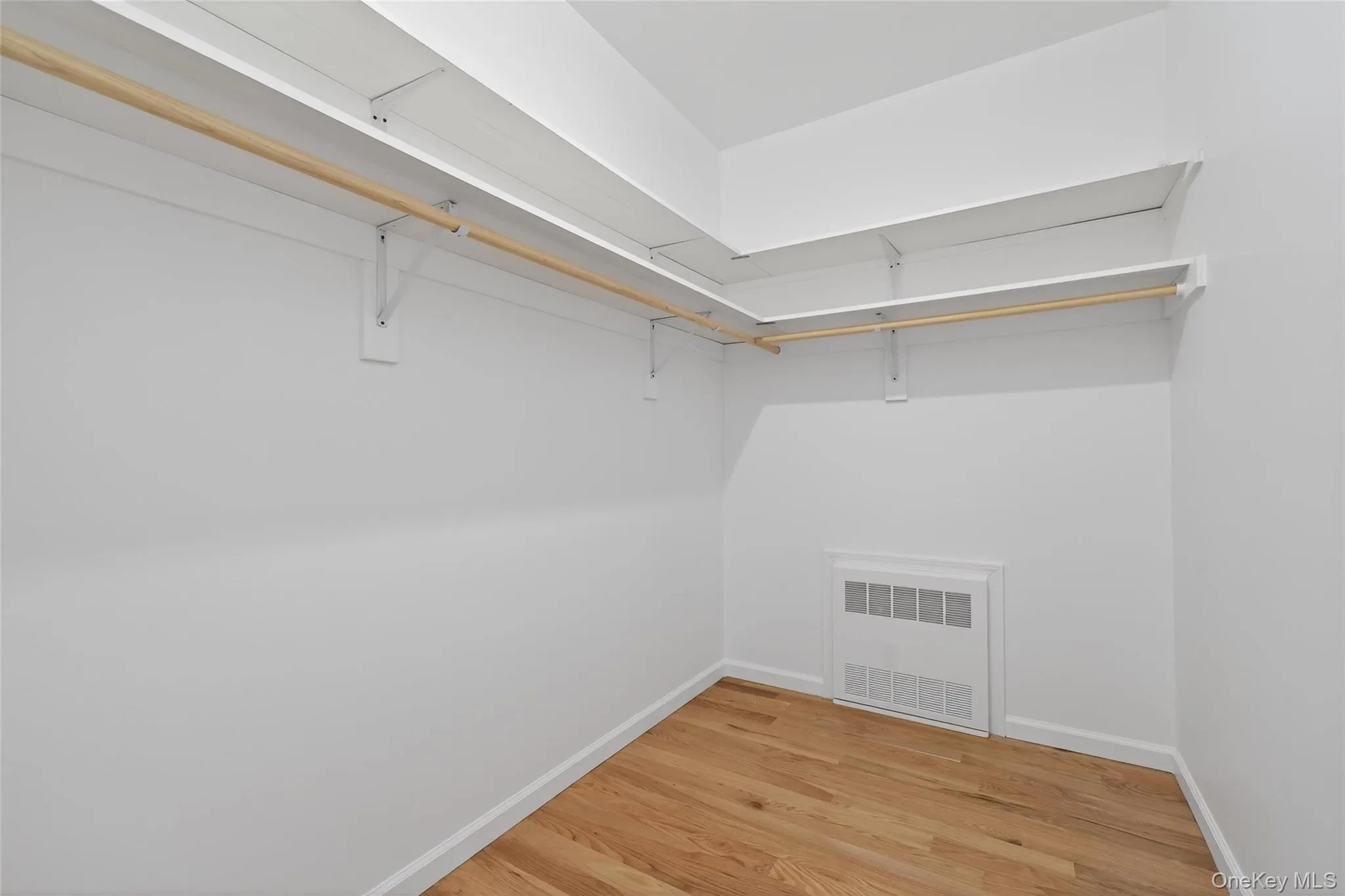 Walk in closet with light wood finished floors and radiator heating unit Walk in closet with light wood finished floors and radiator heating unit
