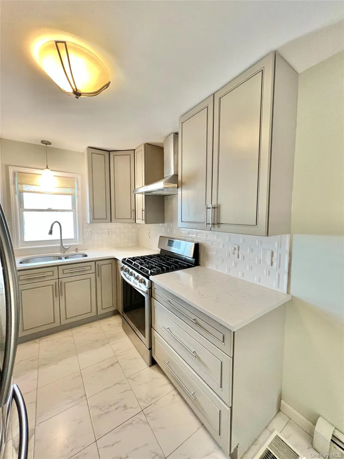 Kitchen with wall chimney range hood, a sink, marble finish floor, stainless steel appliances, and decorative backsplash Kitchen with wall chimney range hood, a sink, marble finish floor, stainless steel appliances, and decorative backsplash