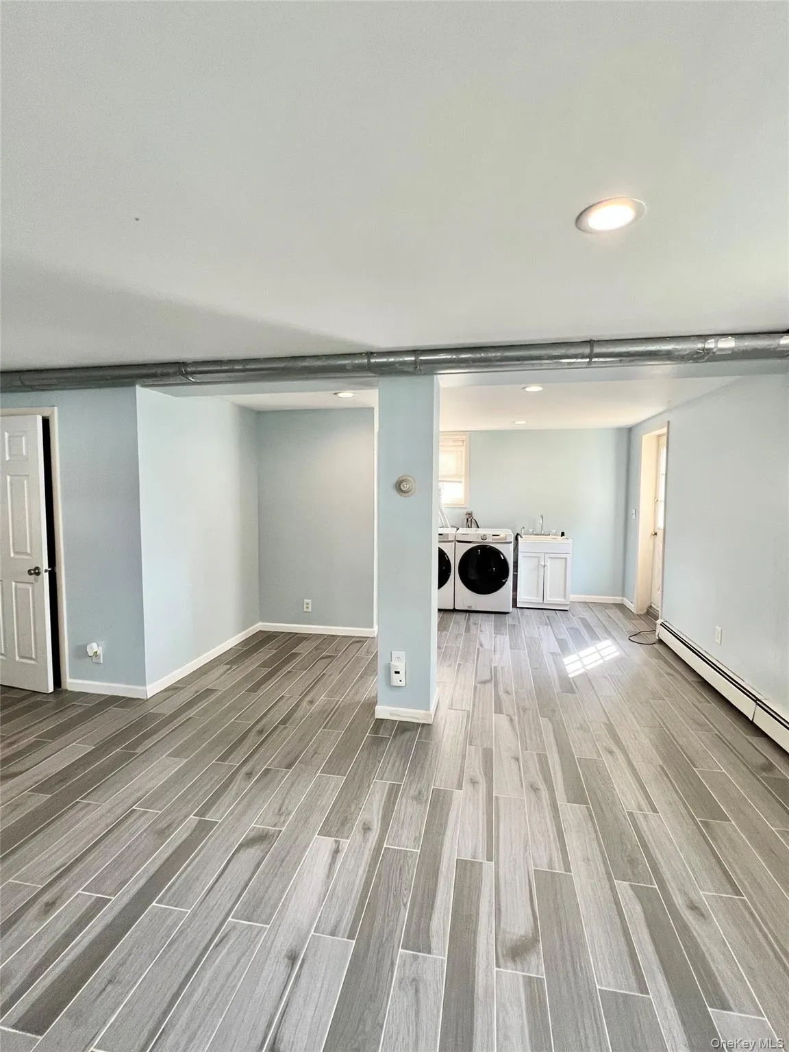 Below grade area featuring recessed lighting, baseboards, light wood-type flooring, and washer and clothes dryer Below grade area featuring recessed lighting, baseboards, light wood-type flooring, and washer and clothes dryer