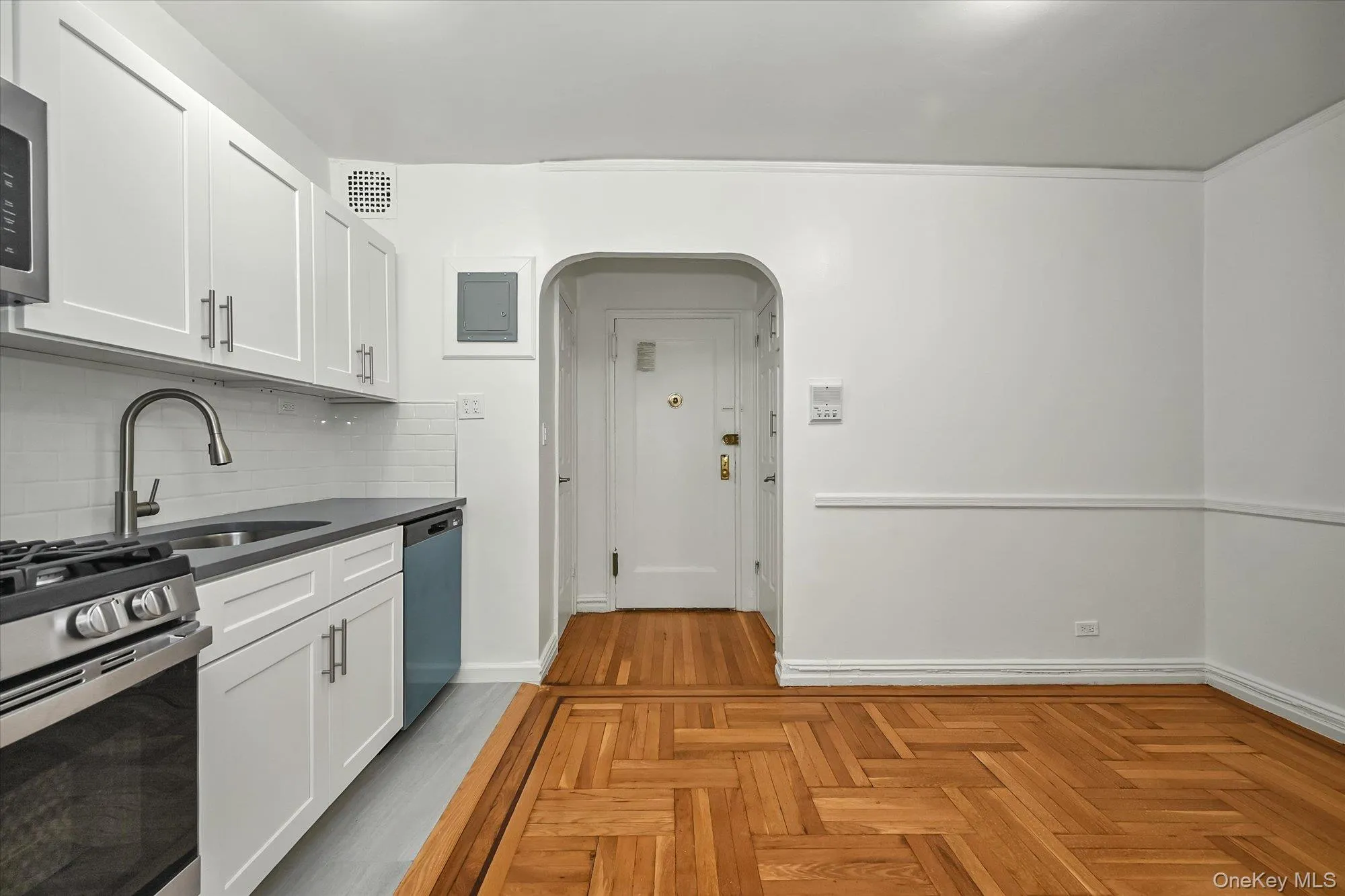 Kitchen with arched walkways, featuring white cabinets, quartz countertops, and parquet floors. Kitchen with arched walkways, featuring white cabinets, quartz countertops, and parquet floors.